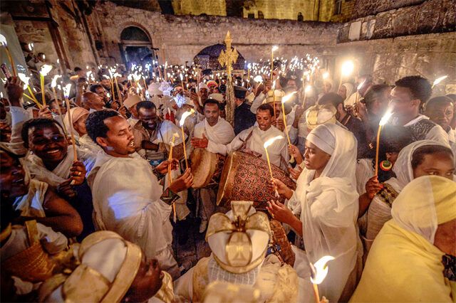 Worshippers singing and drumming with candles during Fasika night service